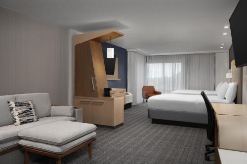 a hotel room with a bed and a couch at Courtyard by Marriott Philadelphia Bensalem in Bensalem
