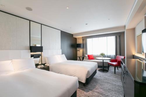 a hotel room with two beds and a television at Nagoya Tokyu Hotel in Nagoya