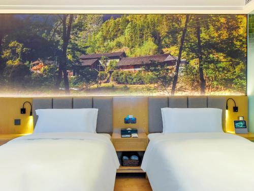 two beds in a room with a large window at 秋果酒店-重庆两江幸福广场店 in Chongqing