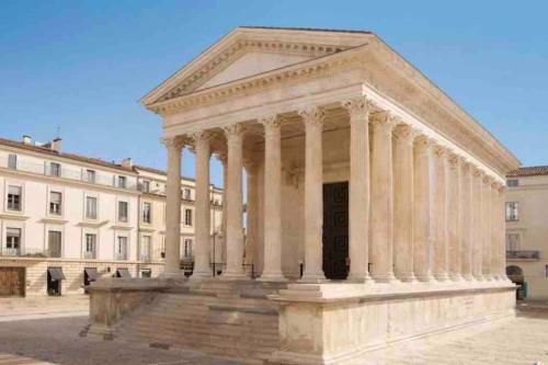 un grand bâtiment avec colonnes devant un bâtiment dans l'établissement Le Vendome, à Nîmes