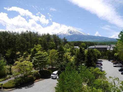 a snow covered mountain with cars parked in a parking lot at Hotel Regina Kawaguchiko in Fujikawaguchiko