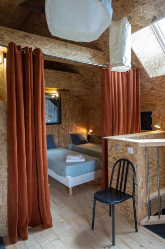 une chambre avec un lit et une chaise dans une pièce dans l'établissement La Ferme du golf, gîte atypique et artistique, à Lancieux