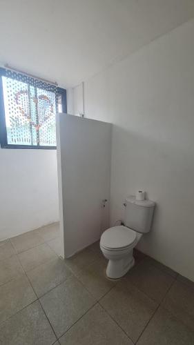 a white bathroom with a toilet and a window at Koh Mak Garden View for Family&Friends in Ko Mak