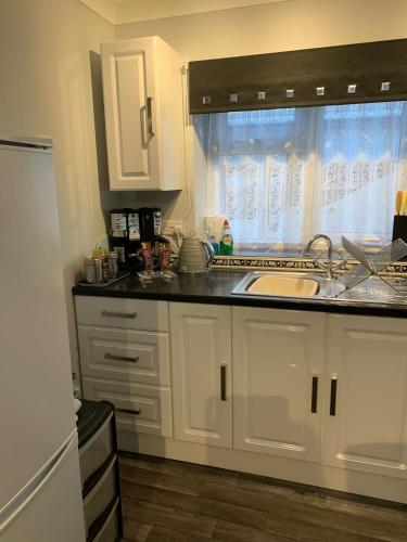 a kitchen with white cabinets and a sink and a window at The Hideaway in Hockering