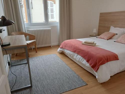 une chambre avec un lit, une table et un bureau dans l'établissement Le Petit Appart au coeur de Vichy, à Vichy