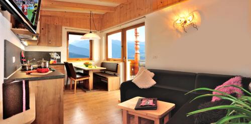 a living room with a black couch and a kitchen at Pitznerhof in Maranza