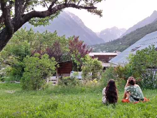 two women sitting in the grass in a field at B&B l'Edelweiss in Vallouise