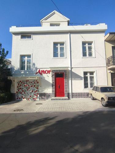 a white building with a red door on a street at Anor in Tashkent