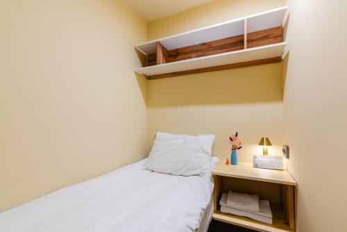 a small bedroom with a bed and a shelf at AYKUN Capsule Hotel in Almaty
