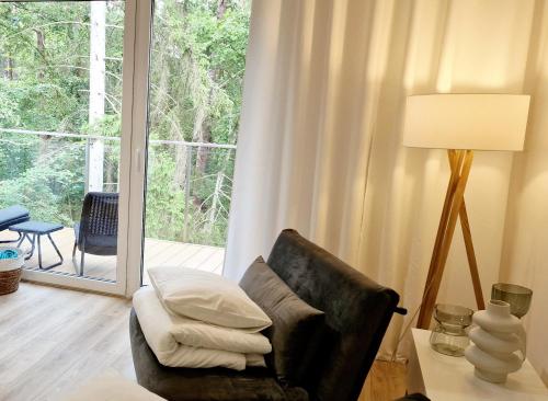 a living room with a chair and a lamp and a window at Pobierowo City in Pobierowo