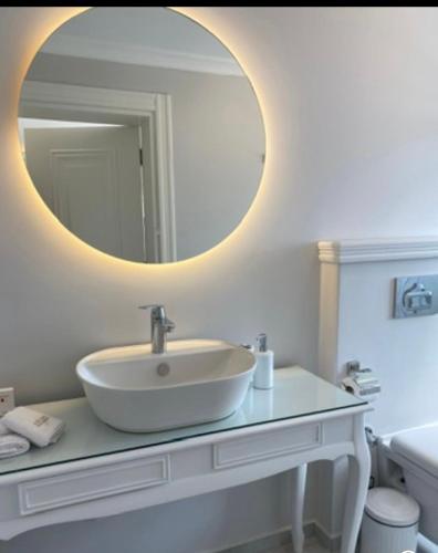 a white bathroom with a sink and a mirror at Aşiyan Yalısı in İznik