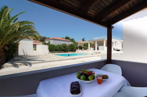a table with a bowl of fruit on a balcony with a pool at Villa SteMMa in Chania Town