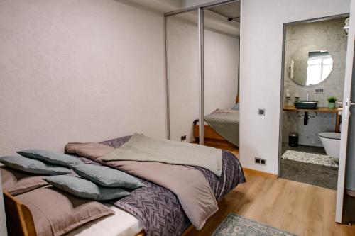 a bedroom with a bed and a bathroom with a mirror at Hales Old Town Urban Apartments in Vilnius