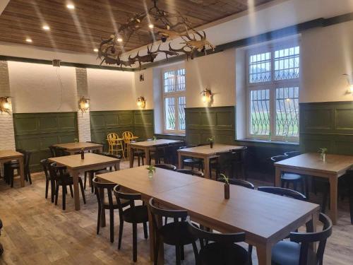 restauracja z drewnianymi stołami i krzesłami oraz oknami w obiekcie Penzion a Restaurace Bělecký Mlýn w mieście Ptení
