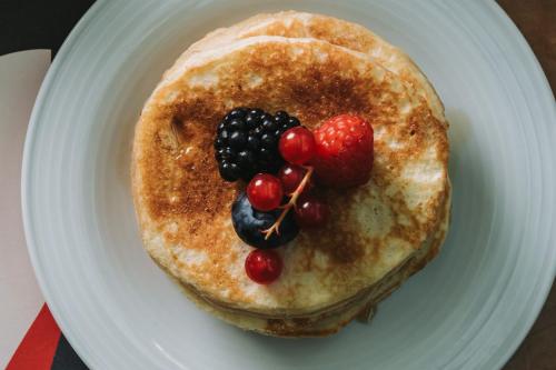 a white plate with a pancake with fruit on it at Royal Garden Assago Milano in Assago