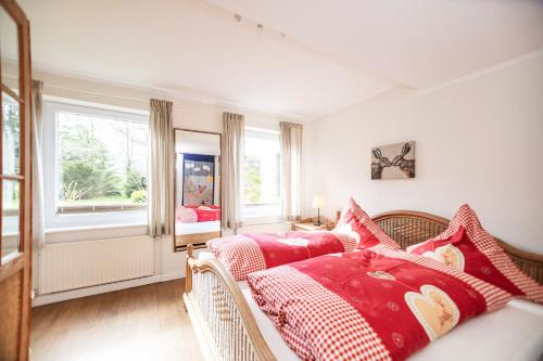 a bedroom with a bed with red and white pillows at Immenhagen Ferienwohnungen in Malente