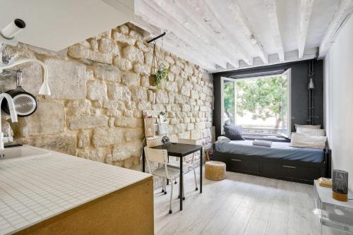 Il comprend une cuisine et un salon avec un mur en pierre. dans l'établissement Charmant studio près du Marais, à Paris