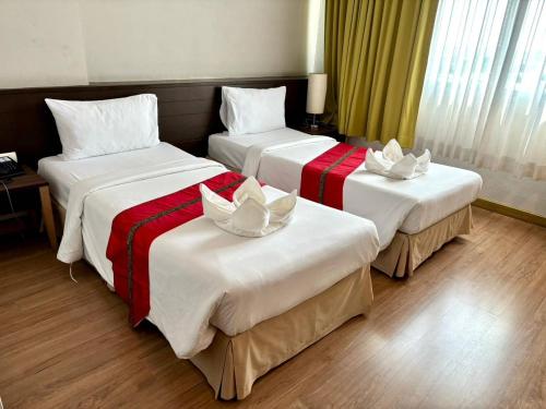 a hotel room with three beds with bows on them at Aloha Hatyai Hotel in Hat Yai