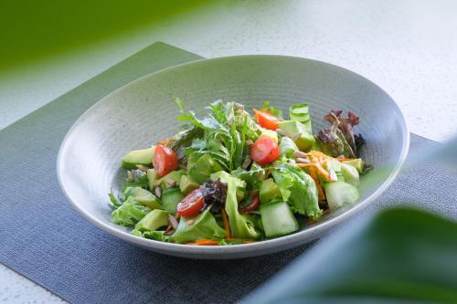 a salad in a white bowl on a table at Aster Apartment Bali in Canggu