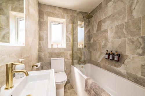 a bathroom with a toilet and a tub and a sink at Bungalow Close to South Downs & Beach in Angmering