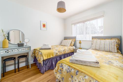 a bedroom with two beds and a mirror at Bungalow Close to South Downs & Beach in Angmering
