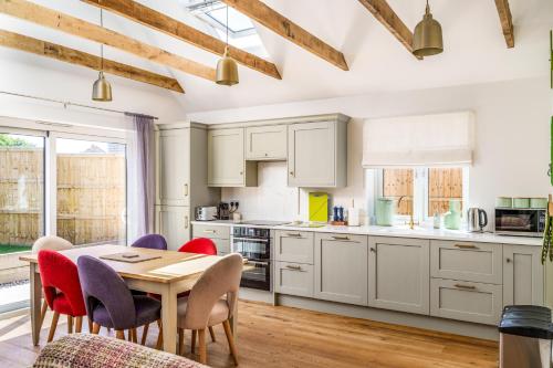 a kitchen with white cabinets and a table and chairs at Bungalow Close to South Downs & Beach in Angmering