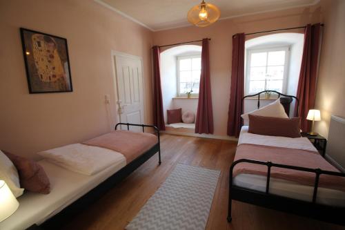 two beds in a room with two windows at Ferienwohnung im Hofratshaus in Schrozberg