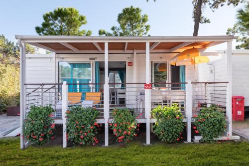 a tiny house with a porch and flowers at Villaggio Turistico Internazionale in Bibione