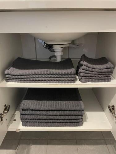 three towels on a shelf under a sink at Sjarmerende hus i Vennesla in Vennesla