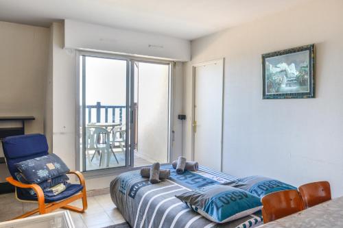 - une chambre avec un lit, une chaise et un balcon dans l'établissement Sur la Promenade Proust - Appt vue mer, à Cabourg