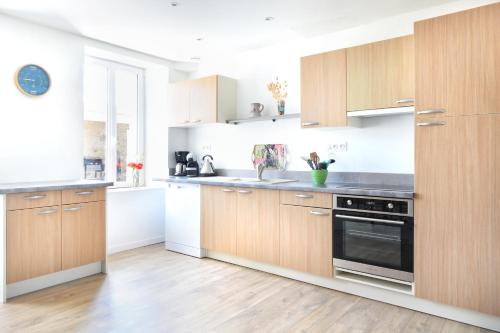 La cuisine est équipée d'armoires en bois et d'un four noir. dans l'établissement Au Boulevard des Dunes - A 50m de la plage, à Saint-Marcouf