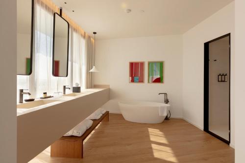 a bathroom with a tub and two sinks and mirrors at Elisabeth by the Sea Hotel in Tossa de Mar