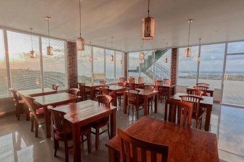a restaurant with tables and chairs and large windows at The Pandan Sari Hotel in Jimbaran