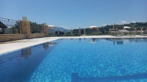a large swimming pool with blue water at Colle Indaco Wine Resort & Spa in Ortezzano