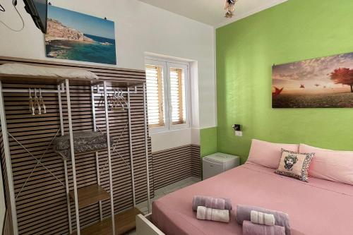 a bedroom with a pink bed and green walls at "Da Nina" in Lascari
