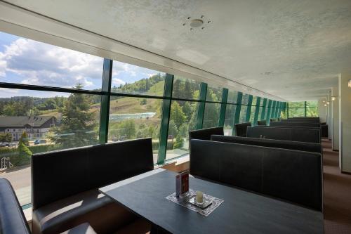 a restaurant with chairs and a table and a large window at Hotel Pegaz in Krynica Zdrój