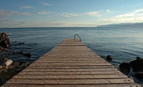 a wooden pier sticking out into the water at Skajado Holiday Apartments in Stalida