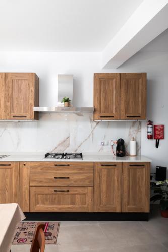 a kitchen with wooden cabinets and a stove at Modern 2BR Stylish Apartment with 2 Balconies - Close to St Julian's & Sliema & Yacht Marina in Tal-Pietà