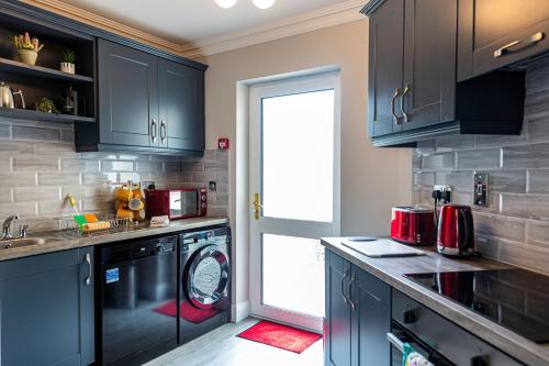 a kitchen with blue cabinets and a washing machine at No 1 Killarney Holiday Village Vacation Home in Killarney