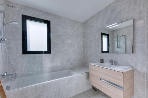 une salle de bain avec une baignoire, un lavabo et un miroir dans l'établissement Alpina - Neuf et Skis aux pieds, à Saint-Gervais-les-Bains