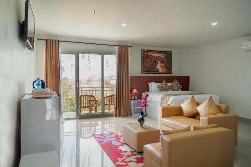 a bedroom with a bed and a couch and a balcony at The Pandan Sari Hotel in Jimbaran