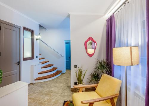 a living room with a yellow chair and stairs at HB apartments Hill House in Tbilisi City