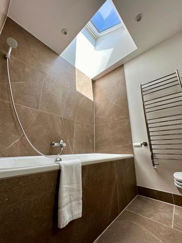 a bathroom with a bath tub and a skylight at Observatory Retreat Luxury Jericho Townhouse with Parking in Oxford