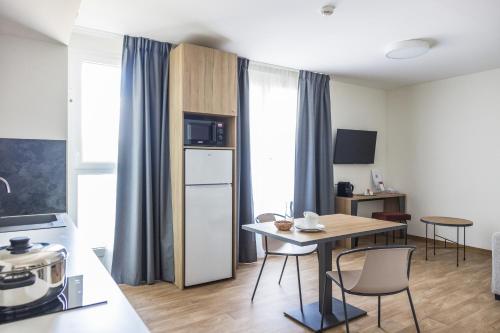 una piccola cucina con tavolo e frigorifero di Hôtel des Thermes des Fumades ad Allegre Les Fumades