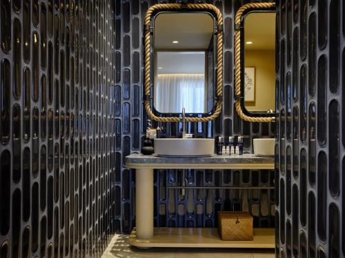a bathroom with two sinks and two mirrors at Atlantica Kalliston Resort - Adults Only in Stalos