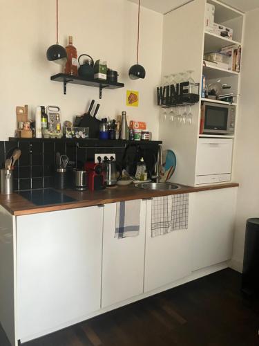 une cuisine avec des armoires blanches et un comptoir dans l'établissement Appartement 9e, à Paris