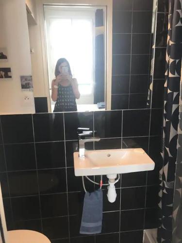une femme prenant une photo dans un miroir de salle de bains dans l'établissement Appartement 9e, à Paris