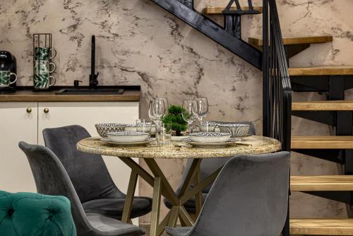 a dining room table with chairs and wine glasses at Sika Grand Palladium Garden & Spa Central Apartment Arad in Arad