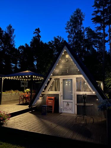 a tiny house with a deck at night at Camping Milk in Usmenieki
