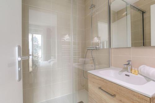 une salle de bain blanche avec un lavabo et une douche dans l'établissement Appartement neuf, clim et parking, Caluire-Dombes, à Caluire-et-Cuire